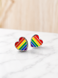 Pride Stud Earrings with rainbow striped heart design in silver on a marble surface