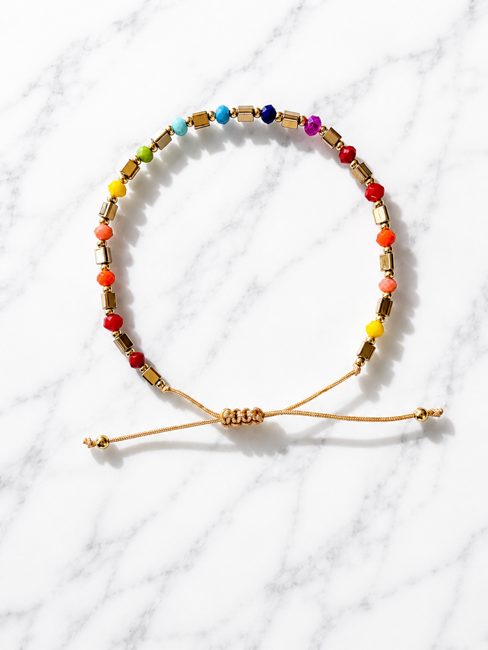 Prism Adjustable Bracelet with multicolor beads and gold tube accents on an adjustable cord, flatlay on marble