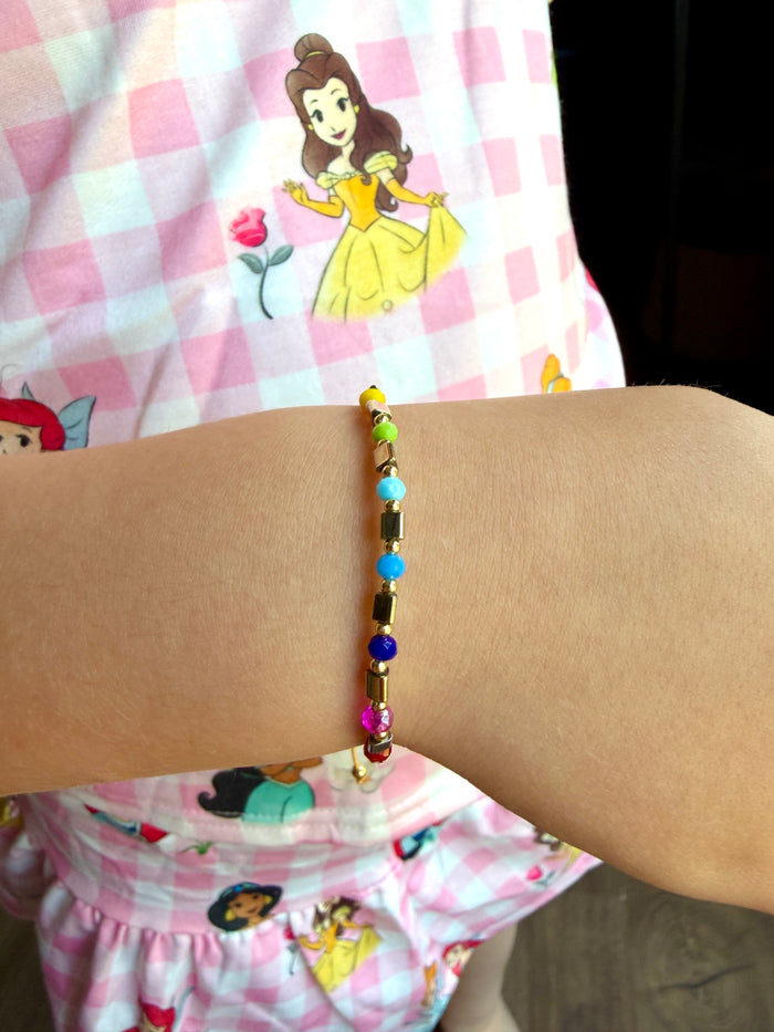 Prism Adjustable Bracelet with multicolor beads worn on a wrist, lifestyle shot on child