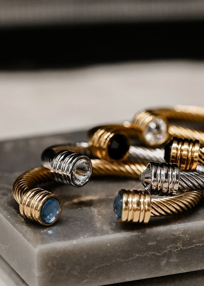 Gold and silver bracelets with blue stones on a gray surface