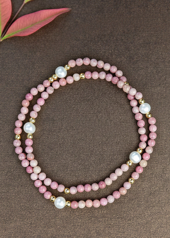 Pink beaded bracelet on a brown surface with green leaves