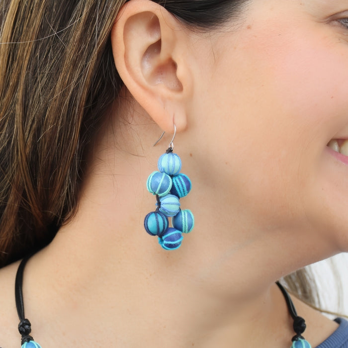 Close-up of a person wearing blue beaded earrings.