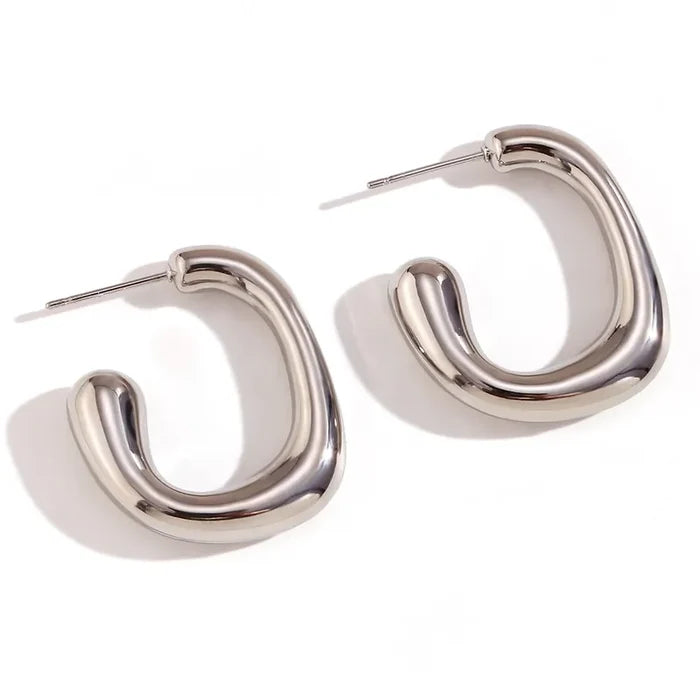 Silver high polish sculptural hoop earrings on white background