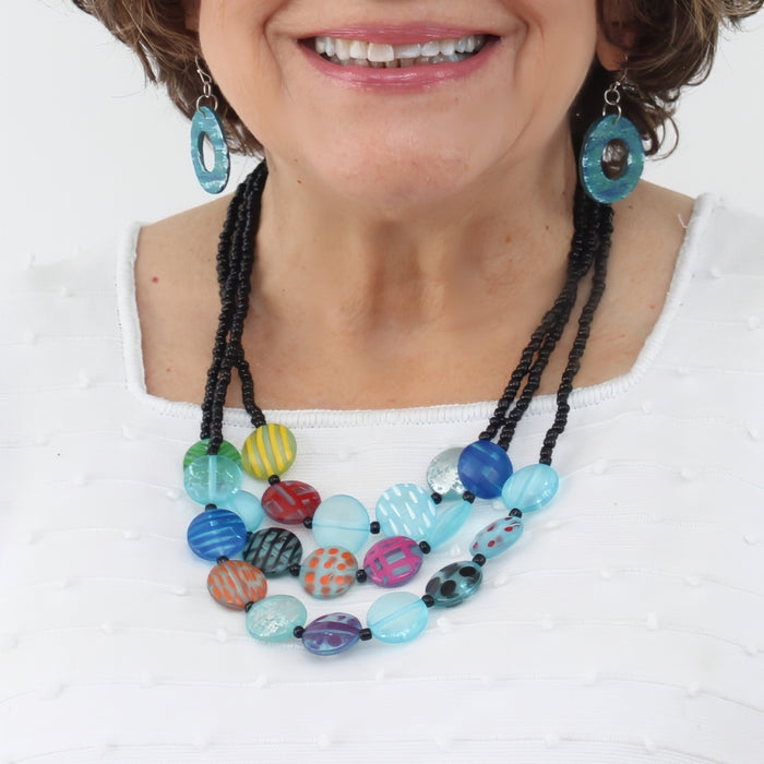 Woman wearing a colorful beaded necklace and earrings on a white background