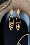 Gold earrings with leopard print details on a black surface