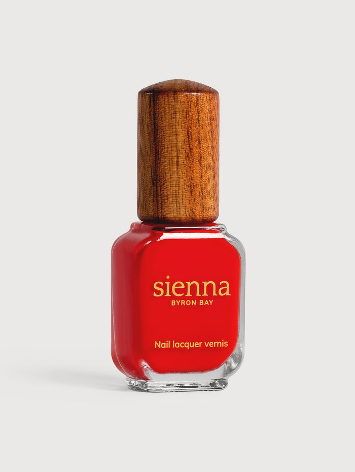 Red nail polish bottle with wooden cap on a white background