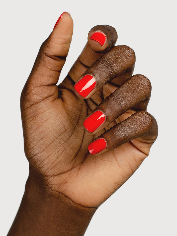 Hand with red nail polish on a plain background