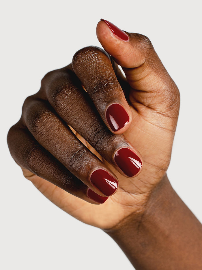 Close-up of a hand with red nail polish on a light gray background