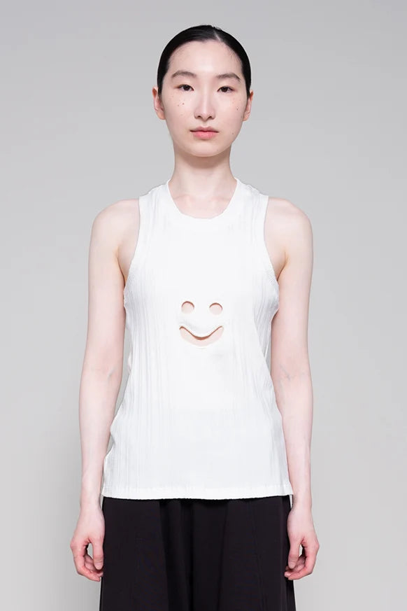 Person wearing a white sleeveless shirt with a smiley face design on a plain background