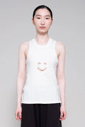 Person wearing a white sleeveless shirt with a smiley face design on a plain background