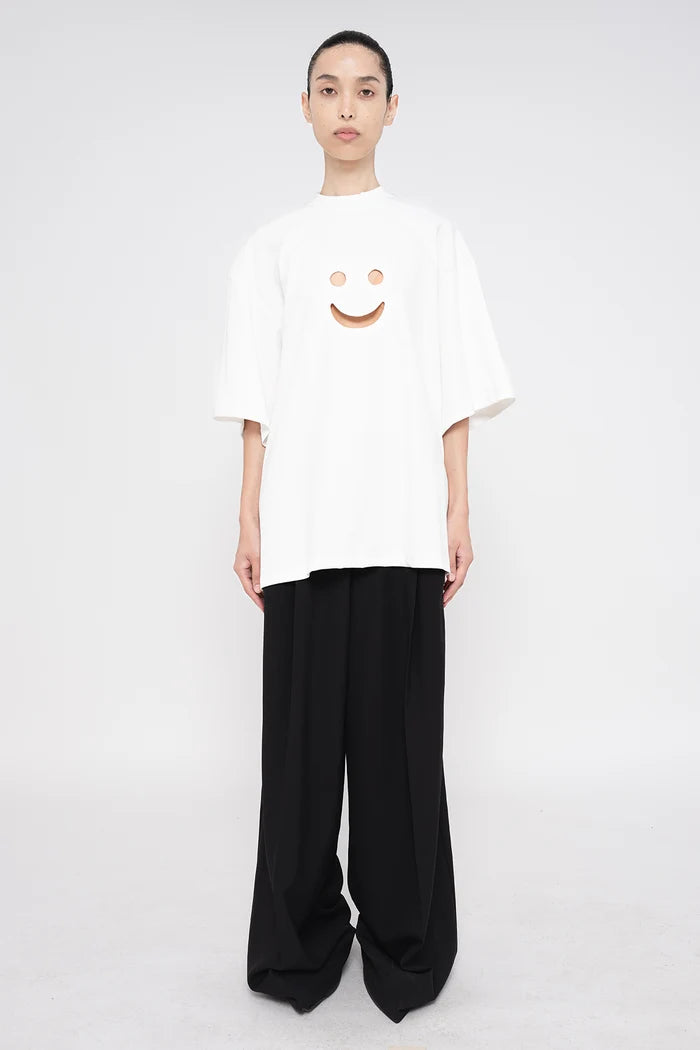 PERSON-WEARING-WHITE-TEE-WITH-SMILEY-FACE-CUT-OUT-AND-BLACK--TAILORED-PANTS-FRONT-VIEW