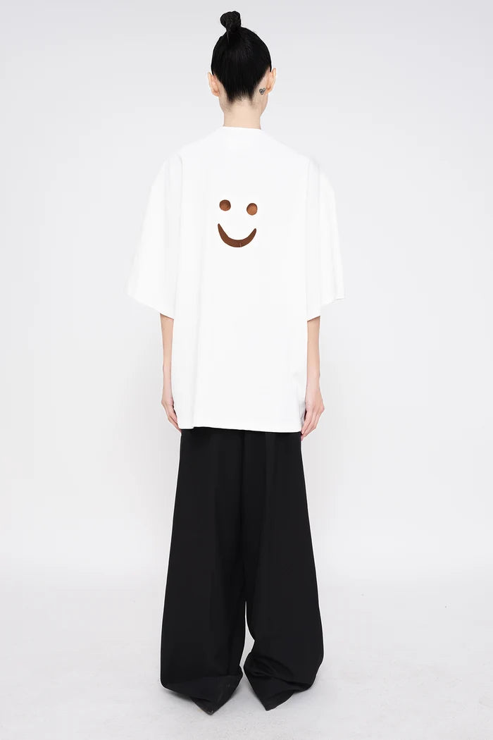 PERSON-WEARING-WHITE-TEE-WITH-SMILEY-FACE-CUT-OUT-AND-BLACK--TAILORED-PANTS-BACK-VIEW
