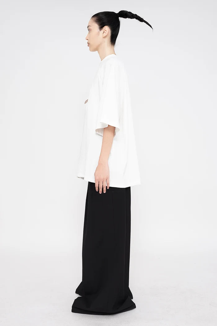 PERSON-WEARING-WHITE-TEE-WITH-SMILEY-FACE-CUT-OUT-AND-BLACK--TAILORED-PANTS-SIDE-VIEW