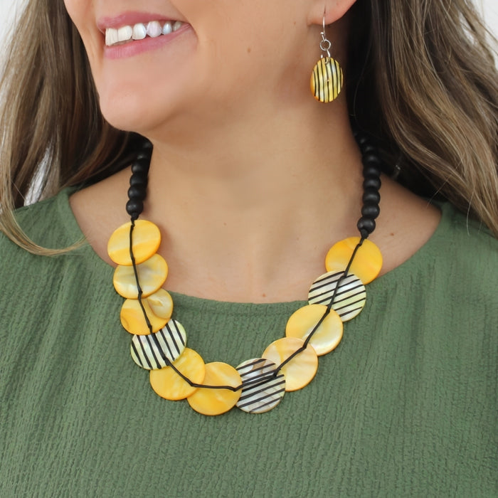 Woman wearing a yellow and black beaded necklace with matching earrings.